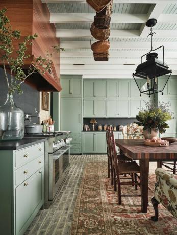 kuchyňa, zelené skrinky, koberček, drevený jedálenský stôl s drevenými stoličkami, drevený digestor, zeleň