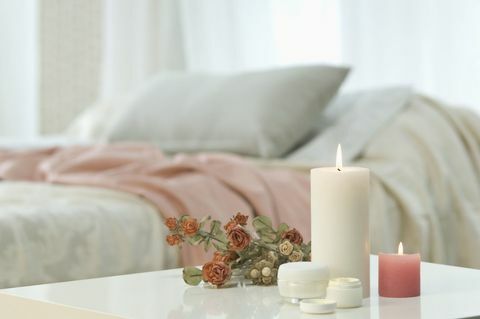 Sviečky, krém na pokožku a veľa ruží na stole s posteľou