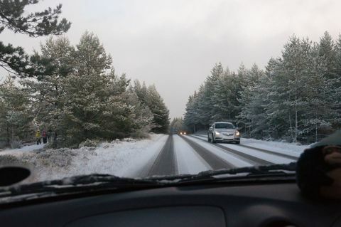 Auto jede po ceste pokrytej snehom medzi stromami