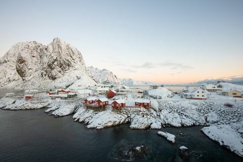 Červená rybárska dedina medzi snehom s výhľadom na hory v ostrove Lofoten Hamnoy v Nórsku