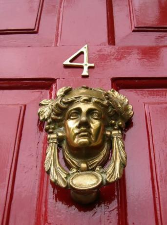 Červené dvere číslo štyri so zlatými klopačmi