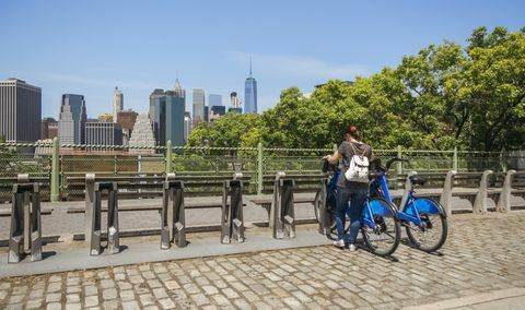 Žena na bicykli pred panorámou Manhattanu v New Yorku