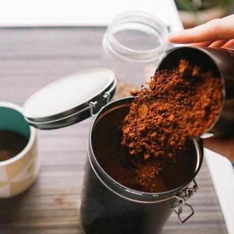 kávová usadenina v záhrade orezané ruky nalievajúce mletú kávu do opakovane použiteľnej nádoby