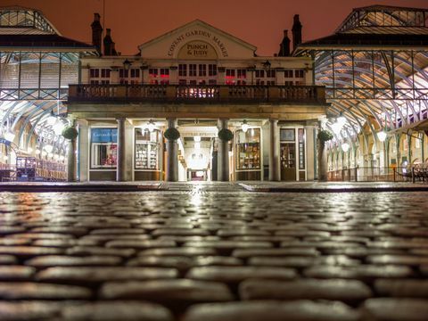 Covent Garden Piazza v noci so svetlami odrážajúcimi sa v dláždení