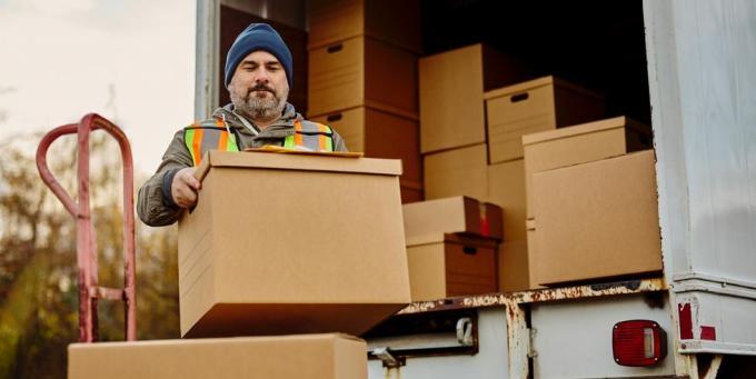 mužský pracovník vykladá kartónové krabice z dodávky