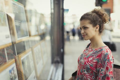 Mladá žena prehliadanie výpisov nehnuteľností v mestských výkladoch