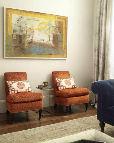 abstraktný obraz nad dvoma oranžovými stoličkami